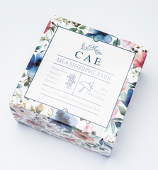 A box of CAE brand nursing pads with a floral pattern on the packaging.