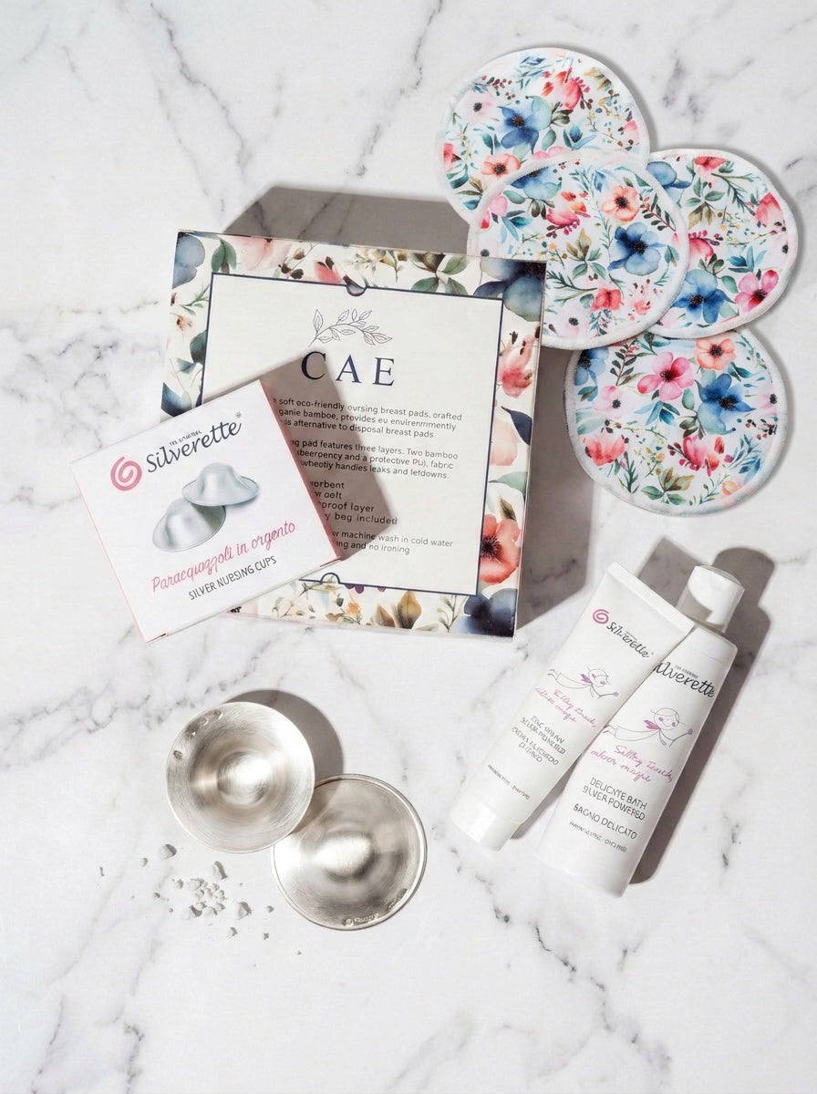 Contents of the Silverette Welcome Baby Gift Set laid out: silver nursing cups, skincare and nursing pads